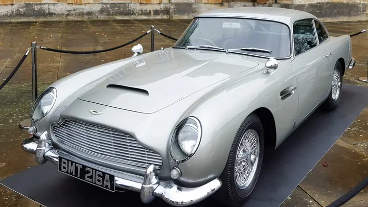 A silver Aston Martin DB5 with the number plate BMT 216A on display in a stone courtyard